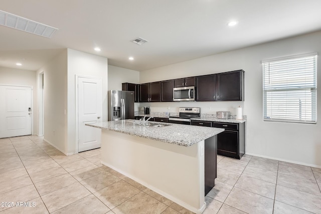 1718 W Cameron Blvd, Coolidge, AZ 85128 - kitchen featuring stainless steel appliances, a sink, light tile patterned flooring, an island with sink, and light stone countertops