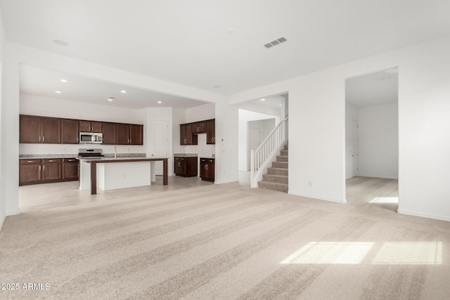 unfurnished living room featuring recessed lighting, visible vents, light carpet, and stairs