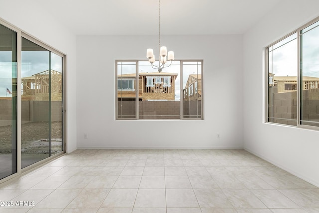 tiled empty room featuring baseboards, plenty of natural light, and a chandelier