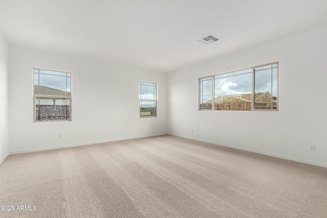 empty room with light colored carpet, visible vents, and baseboards