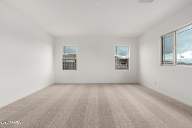 empty room featuring visible vents, baseboards, and light carpet