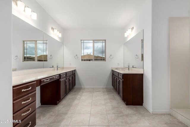 bathroom featuring two vanities, baseboards, and a sink