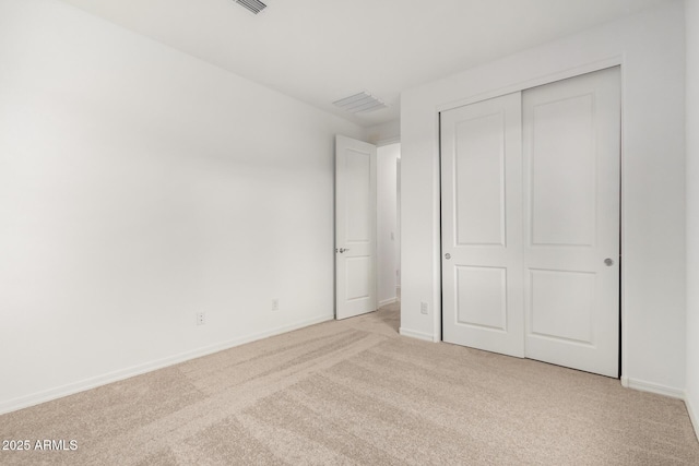 unfurnished bedroom with light carpet, visible vents, a closet, and baseboards