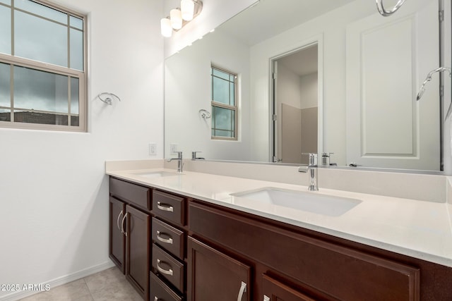 full bath with a sink, baseboards, double vanity, and tile patterned floors