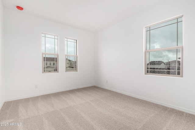 carpeted empty room featuring baseboards