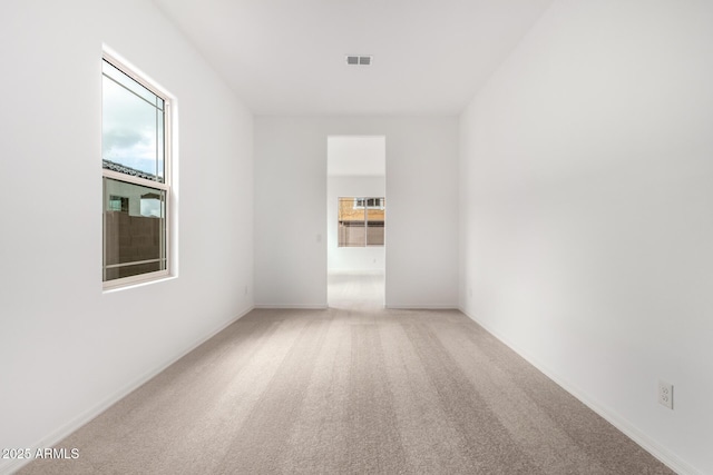 spare room featuring baseboards, visible vents, light carpet, and a healthy amount of sunlight