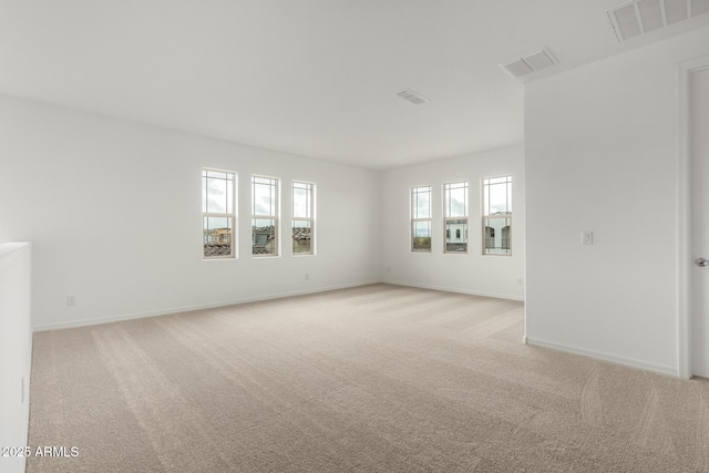 empty room featuring light carpet, visible vents, and baseboards