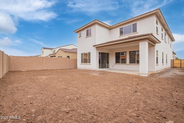 rear view of house featuring stucco siding, a fenced backyard, and a patio area