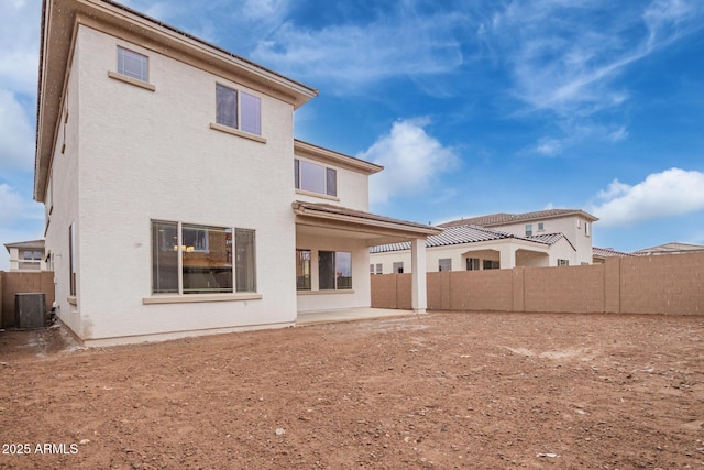 rear view of property with stucco siding, central air condition unit, a fenced backyard, and a patio area