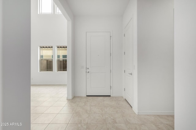 hall featuring light tile patterned floors, baseboards, and a healthy amount of sunlight