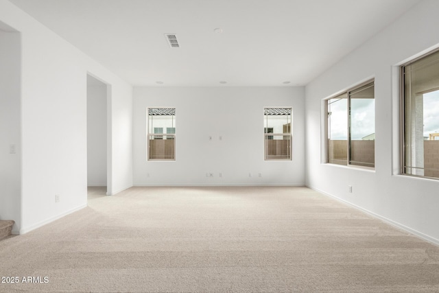 unfurnished room featuring visible vents, light colored carpet, stairs, and baseboards