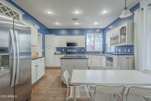 kitchen featuring stainless steel appliances, a center island, wood finished floors, white cabinetry, and recessed lighting