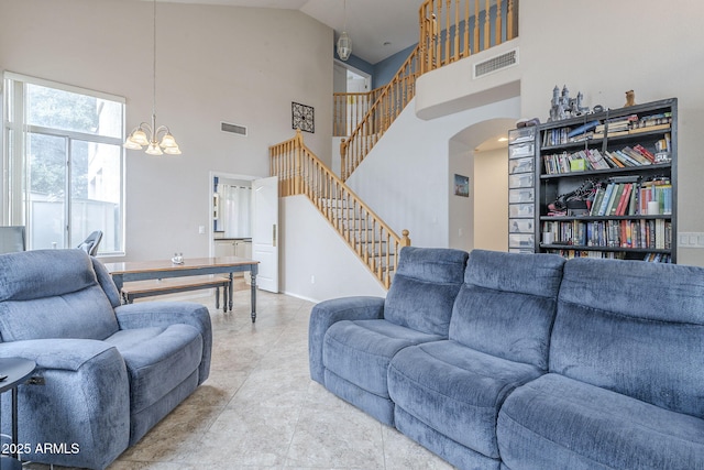 living room featuring stairway, arched walkways, a chandelier, and a towering ceiling