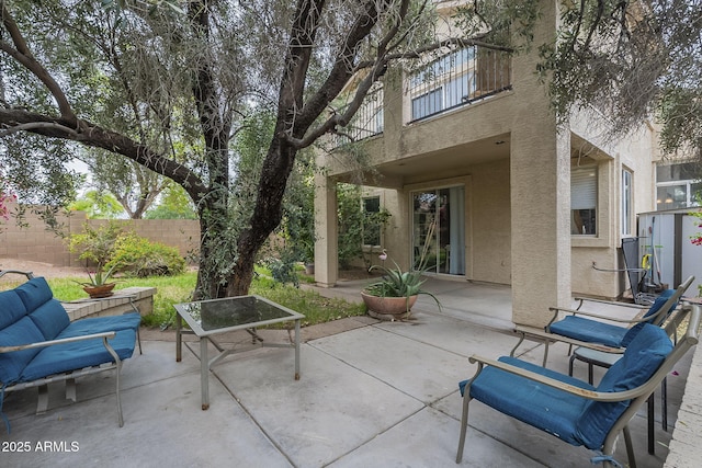 view of patio with fence, an outdoor living space, and a balcony