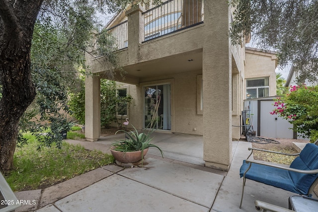 back of house featuring stucco siding, a shed, a patio, and a balcony