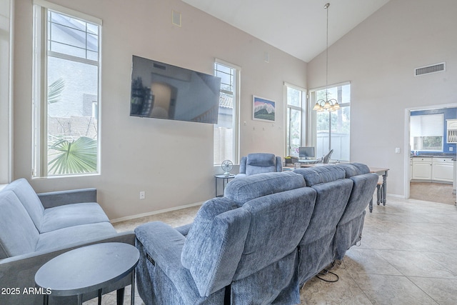 living area with a chandelier, high vaulted ceiling, and baseboards