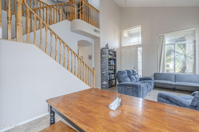 dining area with a high ceiling, stairway, arched walkways, and baseboards