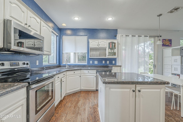 kitchen with stainless steel appliances, light wood-style floors, a kitchen island, white cabinets, and recessed lighting
