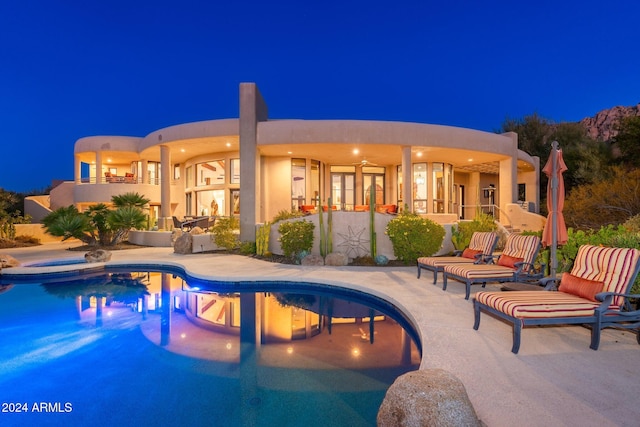 pool at twilight featuring an in ground hot tub and a patio