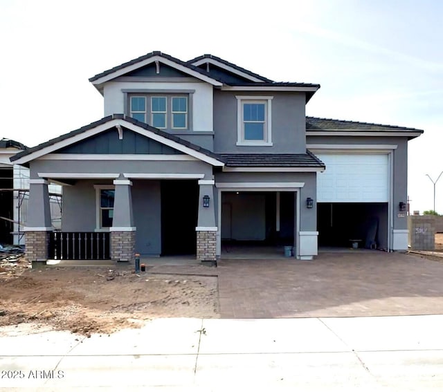 craftsman inspired home with stucco siding, a tiled roof, decorative driveway, and a garage