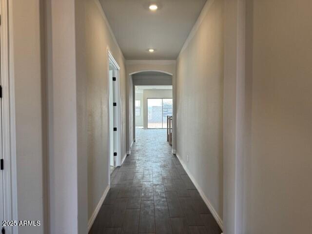 hall featuring ornamental molding, recessed lighting, arched walkways, baseboards, and dark wood-style flooring