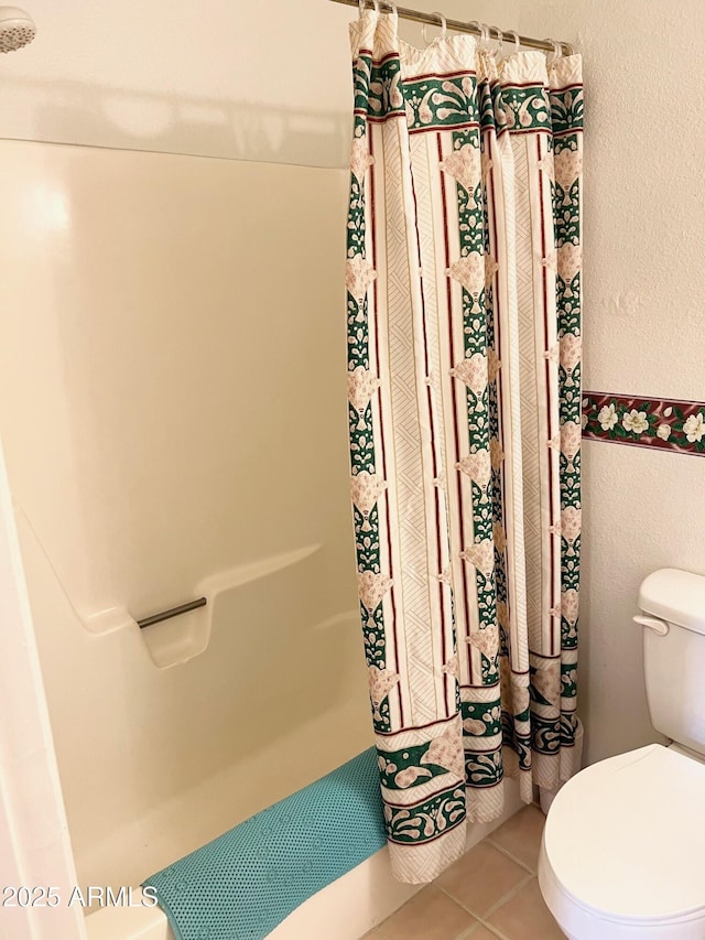 full bathroom featuring a shower with shower curtain, tile patterned flooring, and toilet