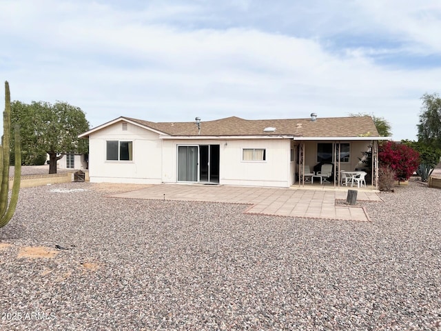 rear view of house featuring a shingled roof and a patio