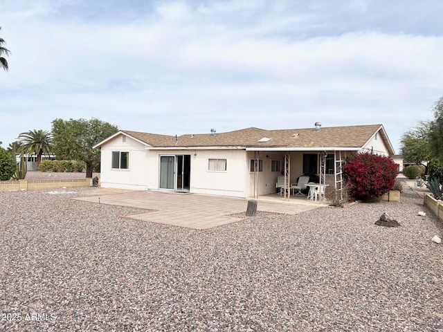 rear view of house with roof with shingles and a patio area