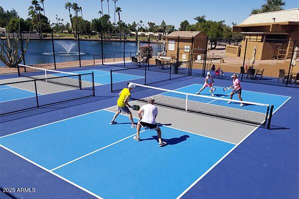 view of sport court with a water view and fence