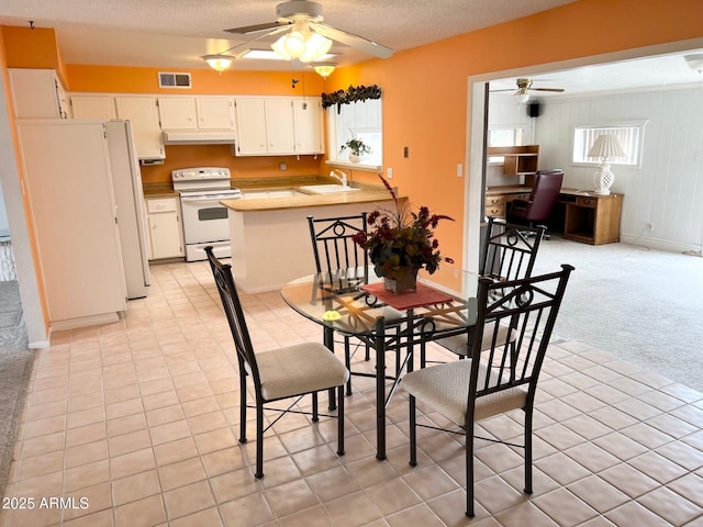 dining room featuring baseboards, a ceiling fan, visible vents, and light colored carpet