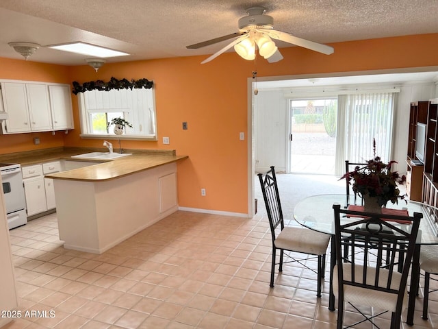 unfurnished dining area featuring light tile patterned floors, ceiling fan, a sink, a textured ceiling, and baseboards