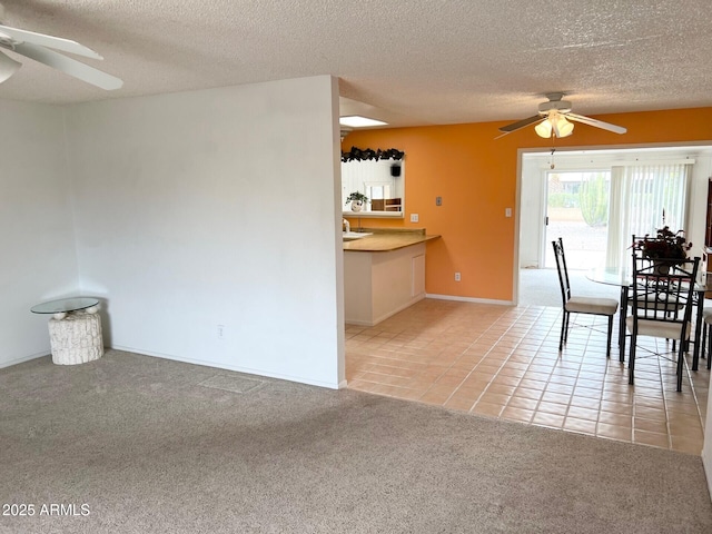 unfurnished dining area with a textured ceiling, light tile patterned flooring, a ceiling fan, and light colored carpet