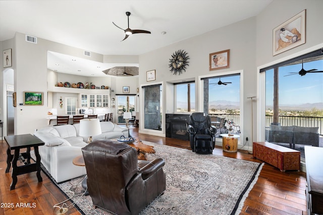 living area featuring wood-type flooring, visible vents, a fireplace, and ceiling fan