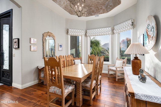 dining space with a chandelier, visible vents, baseboards, a tray ceiling, and dark wood finished floors