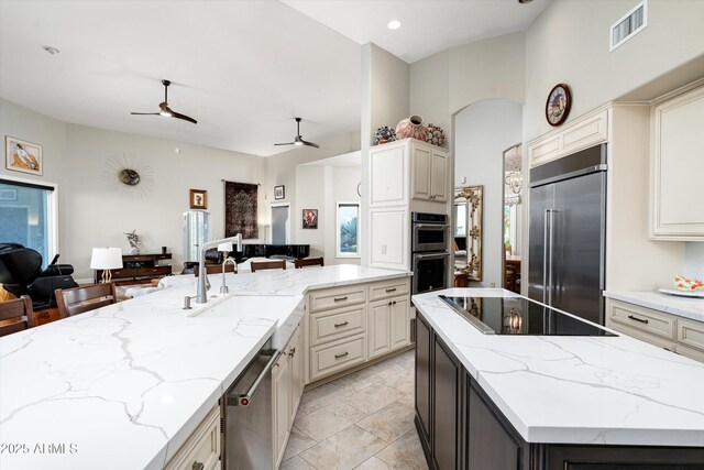 kitchen featuring stainless steel appliances, a sink, visible vents, open floor plan, and a center island