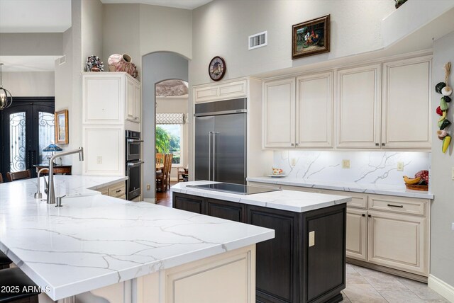 kitchen with a center island, built in refrigerator, black electric cooktop, double oven, and backsplash