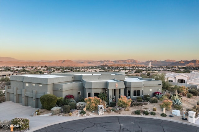 southwest-style home featuring a garage, a mountain view, and stucco siding