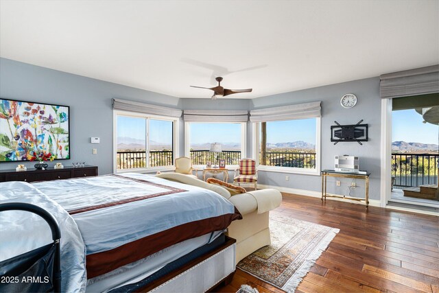 bedroom with a mountain view, a ceiling fan, baseboards, access to outside, and hardwood / wood-style floors