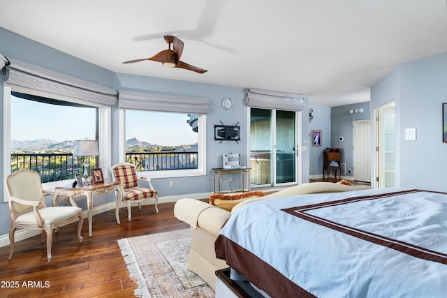 bedroom featuring baseboards, a ceiling fan, wood finished floors, access to exterior, and a mountain view