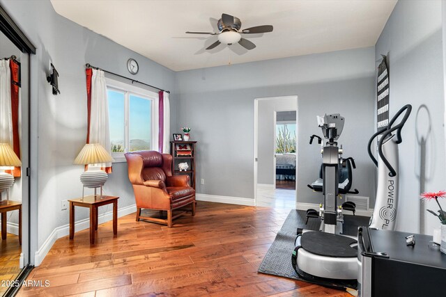 exercise area featuring wood-type flooring, a ceiling fan, and baseboards