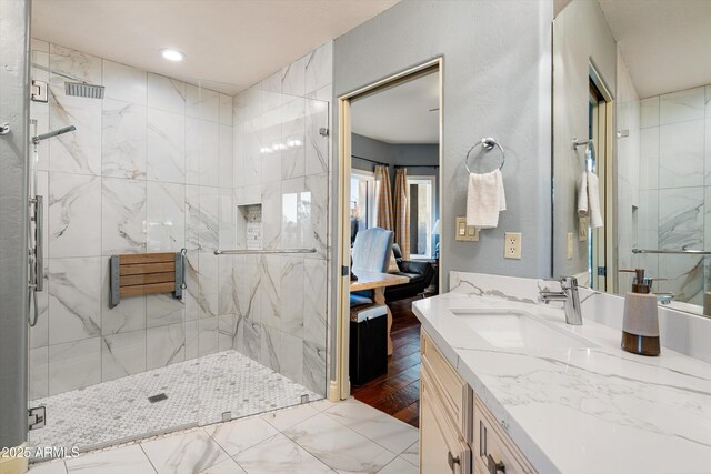 bathroom featuring a marble finish shower, vanity, and recessed lighting