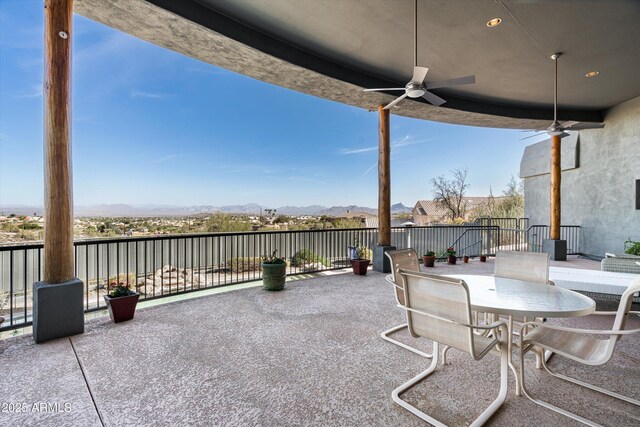 view of patio featuring a ceiling fan, outdoor dining space, and a mountain view