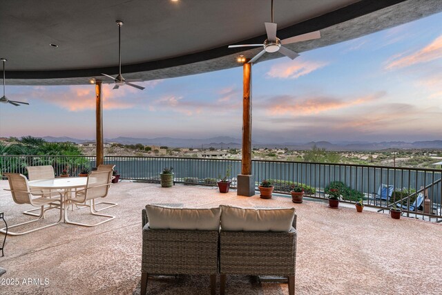 patio terrace at dusk with ceiling fan, outdoor dining space, and a mountain view