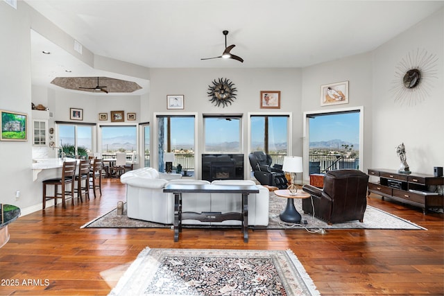 living room featuring a ceiling fan, wood-type flooring, and a healthy amount of sunlight