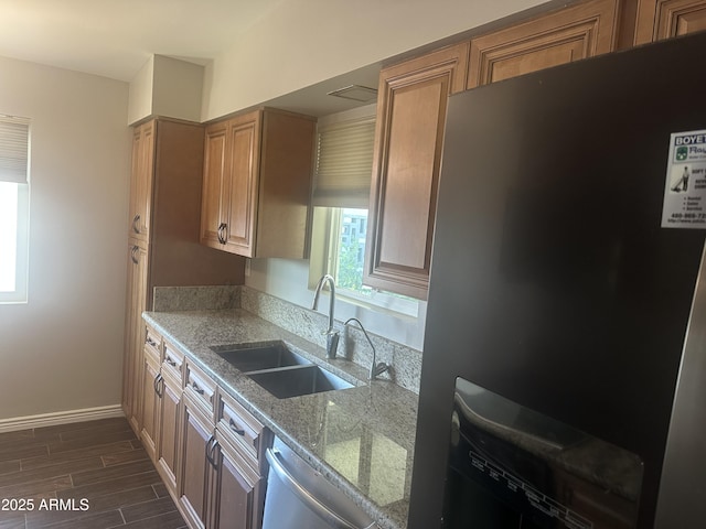 kitchen with stainless steel appliances, light stone countertops, and sink