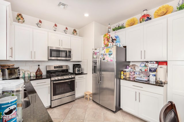 kitchen with dark stone countertops, white cabinets, and stainless steel appliances