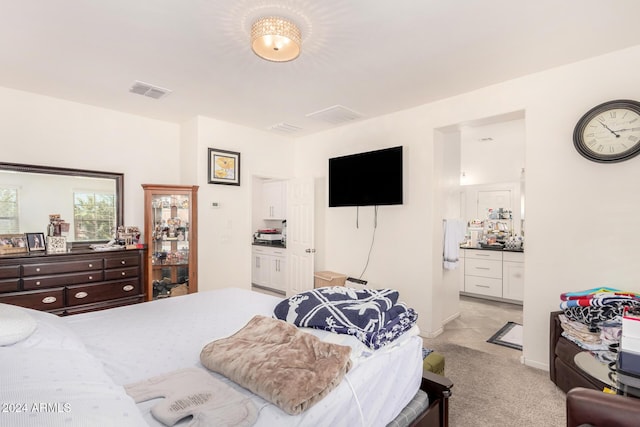 bedroom featuring light colored carpet and ensuite bath