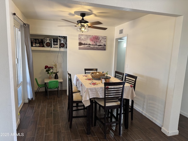 dining area featuring baseboards, visible vents, a ceiling fan, and wood tiled floor