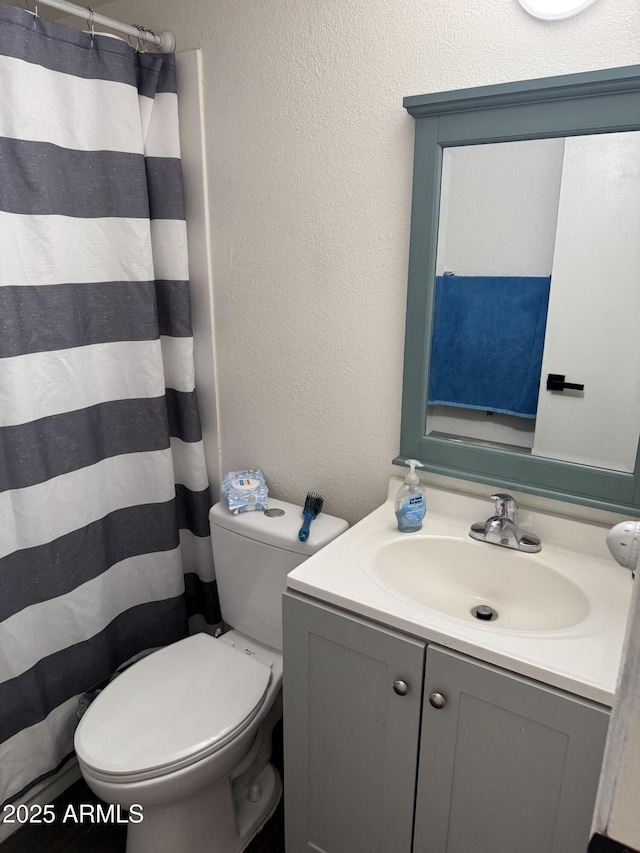 full bath featuring toilet, a textured wall, vanity, and a shower with shower curtain