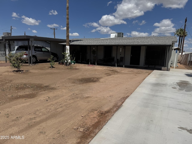 view of front of house with a porch, a carport, and dirt driveway